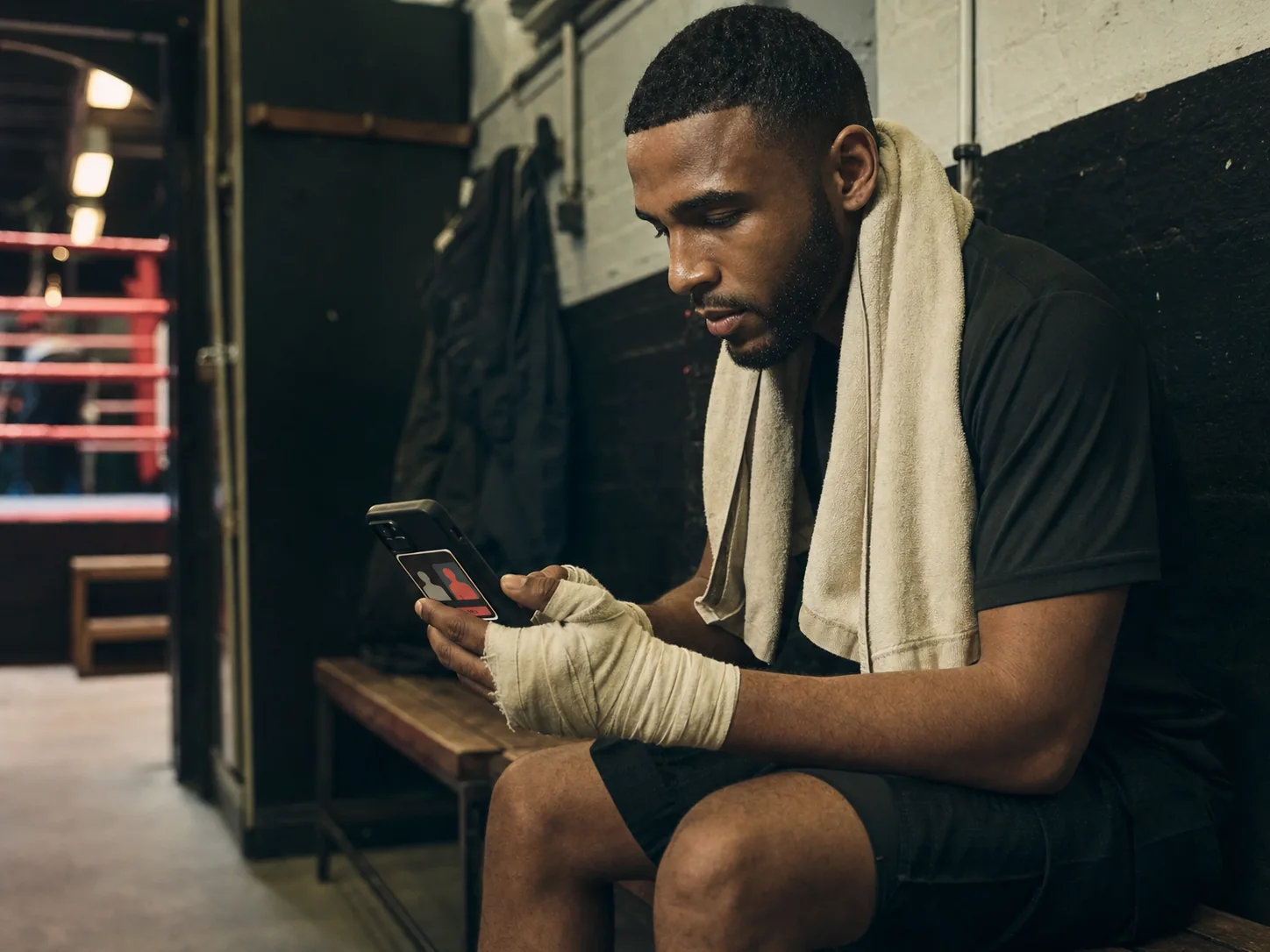 An adult amateur boxer reviewing a matchup on a phone after training